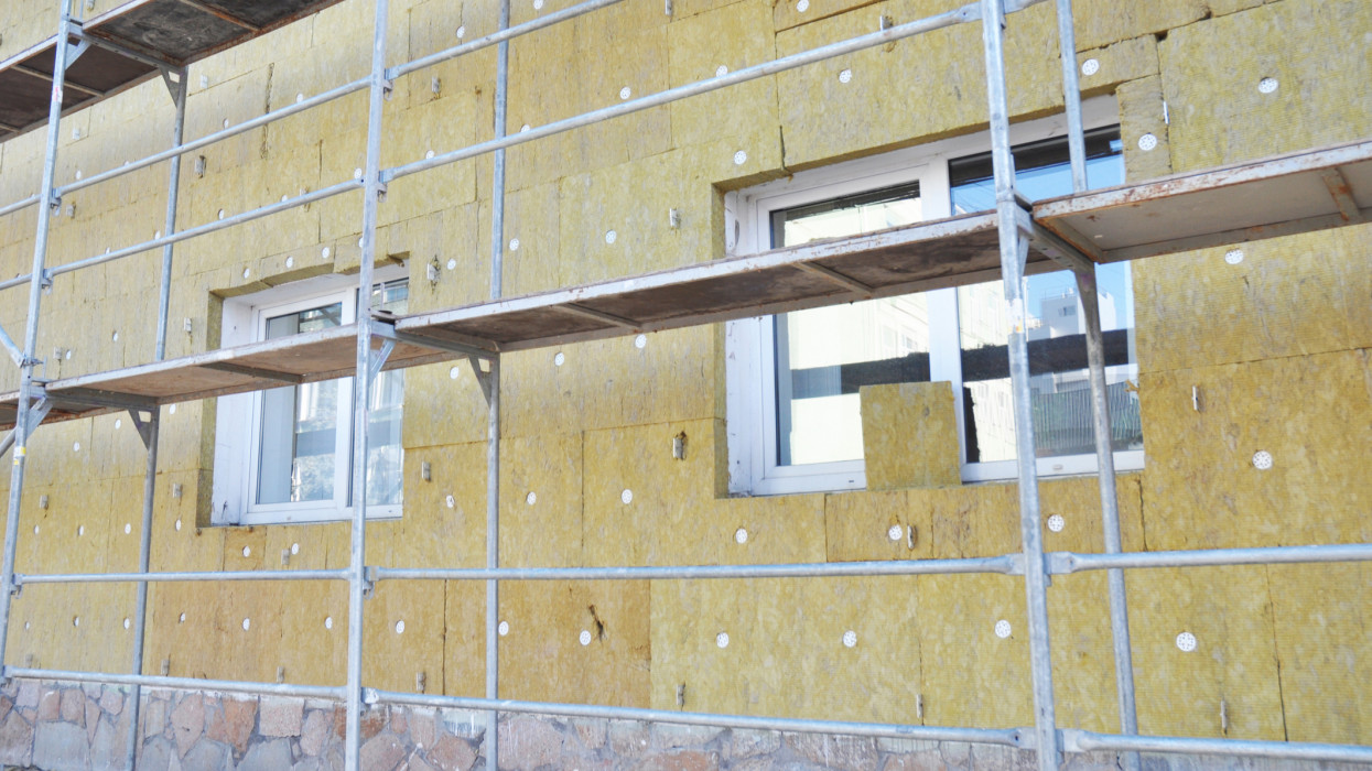 Install Rock Mineral Wool Insulation. Energy efficiency house wall  renovation for energy saving. Exterior house wall heat insulation with mineral wool, building under construction.